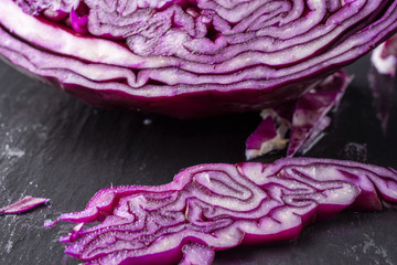 Obraz premium Macro closeup of detail of pieces of red cabbage, with selective focus, on black background, horizontal