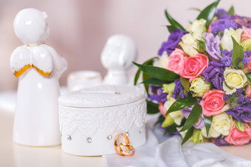 Composition of a wedding bouquet, white gloves of the bride, a white ceramic box and wedding rings.
