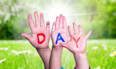 Children Hands Building Colorful Word Day. Sunny Green Grass Meadow As Background