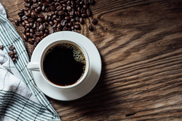 Hot black coffee cup and coffee beans on wooden background with natural light in the morning