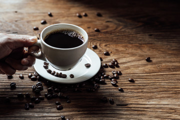 Hot black coffee cup and coffee beans on wooden background with natural light in the morning
