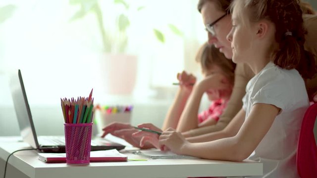 Online distance learning for children. Son and daughter use a laptop for education. Mom helps with homework during the worldwide coronavirus epidemic covid19. Stay home concept.