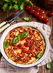 Quiche open tart pie with ham and tomatoes filled with cream, cheese and eggs. Savory taste.