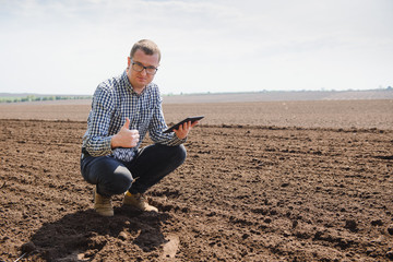 farmer sitting in a plowed field. Agriculture, crop concept.