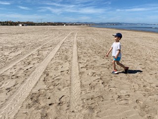 A child walks along a deserted beach on a hot summer day.