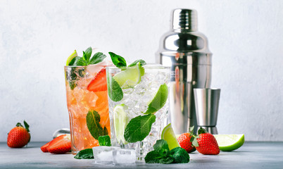 Fresh Mojito cocktail set with lime, mint, strawberry and ice in glass on gray background. Summer...