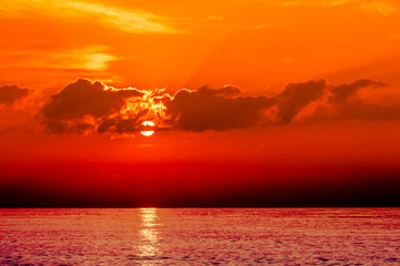Sunset on the orange sea. Evening sky with clouds. Orange color highlights the texture of clouds and ocean. Here shows the game of the setting sun.
