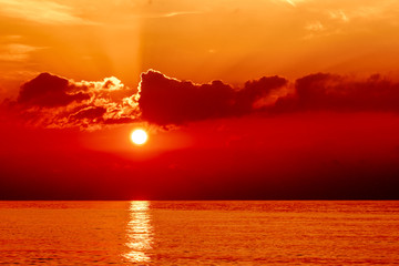 Sunset on the orange sea. Evening sky with clouds. Orange color highlights the texture of clouds and ocean. Here shows the game of the setting sun.