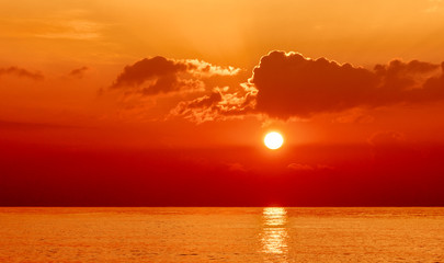 Sunset on the orange sea. Evening sky with clouds. Orange color highlights the texture of clouds and ocean. Here shows the game of the setting sun.