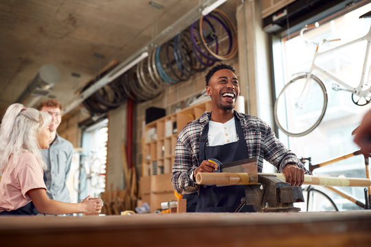 Multi-Cultural Team In Workshop Assembling Hand Built Sustainable Bamboo Bicycle Frame