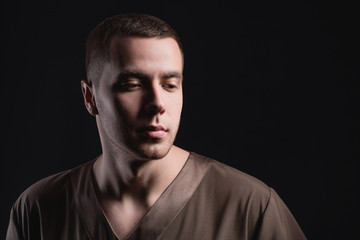 Fototapeta premium Attractive young man in standing with a pensive look on a dark background. Studio photography