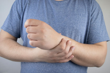 A man’s wrist hurts. Traumatologist examines a hand. Wrist pain as a sign of tunnel syndrome or sprain, tendon degeneration, arthritis