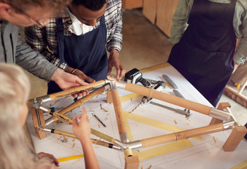 Multi-Cultural Team In Workshop Assembling Hand Built Sustainable Bamboo Bicycle Frame