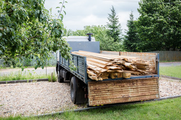 A planed board lies on board the truck. Building materials were brought to the construction site. Chopped wood for interior use.