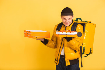 Holding pizzas boxes. Emotions of caucasian deliveryman isolated on yellow background. Contacless delivery service during quarantine. Man delivers food during isolation. Safety. Hurrying up.