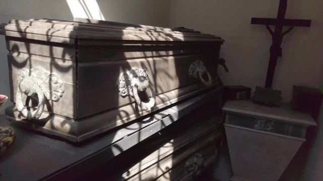 Steps down to a crypt and pan up to several caskets in mausoleum, Buenos Aires 