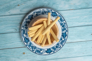 Thai Sweet Sugar Candy Look Like Stick Wood on old Ceramic Dish with Blue Wooden Background, Flat Lay top view angle