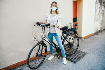 Fototapeta na wymiar Young woman cycling, wearing medical mask