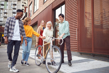 Group Of Multi-Cultural Friends Walking On City Street With Sustainable Bamboo Bicycle 