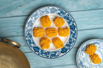 Sweet egg floss on old ceramic dish with blue wooden background - dry sweet egg floss desert Four kind of Thailand traditional dessert, fios de ovos, High Top Flat Lay angle view