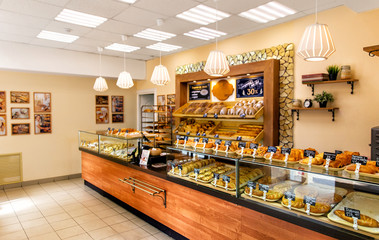 Baked baguettes and pies on showcase in bakery shop. Inscriptions in russian with the name baking - obrazy, fototapety, plakaty
