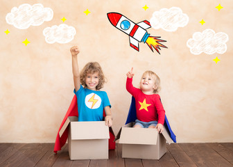 Superheroes children playing in cardboard box