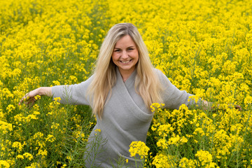 Fototapeta premium Young woman suffers from allergy in a rape field and has to sneeze