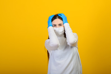 Girl in medical gloves dress a medical mask on her face on a background. Respiratory disease. Covid-19