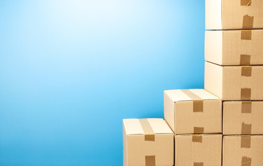 Cardboard boxes steps up for delivery or moving. Stack of boxes and blue background. Copy space for text