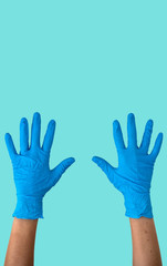 Human rising hands wearing blue disposable latex glove, rubber glove for professional medical safety and hygiene protection from Coronavirus disease COVID-19 and medical surgery on yellow background