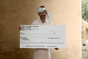 Portrait of Indian rural farmer showing a bank cheque

