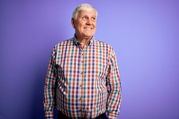 Senior handsome hoary man wearing casual colorful shirt over isolated purple background smiling looking to the side and staring away thinking.