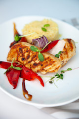 Grilled chicken fillet and pepper. Meat and porridge in a plate with microgreen. White plate with home food close-up. Cutlet and vegetables. Mashed potatoes and a piece of meat.