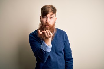Handsome Irish redhead business man with beard standing over isolated background looking at the camera blowing a kiss with hand on air being lovely and sexy. Love expression.
