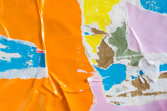 Orange torn and crumpled paper placard on urban billboard with old ripped and peeling posters texture background.
