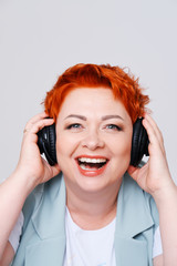 excited redhead woman listening music in headphones