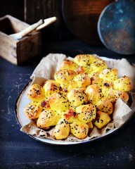 Homemade buns with raisins and sesame seeds on a dark blue wooden background
