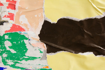 Beige yellow and black torn and crumpled paper placard on urban billboard with old shabby ripped...