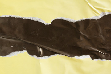 Yellow beige and black torn and crumpled glossy paper placard and poster with rough surface texture...