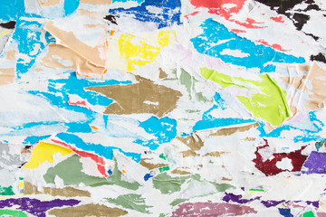 Bright colorful torn crumpled and peeling pieces of old paper placard and poster layers texture background.