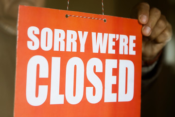 Business store owner turning closed sign at shop doorway