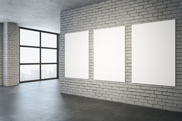 Contemporary brick interior with three blank posters on wall