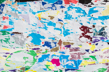 Colorful torn crumpled and peeling pieces of old paper layers on billboard texture background.