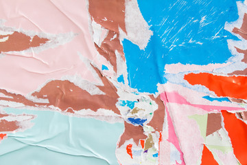 Pink, blue and brown torn crumpled and peeling pieces of old paper poster layers on billboard....