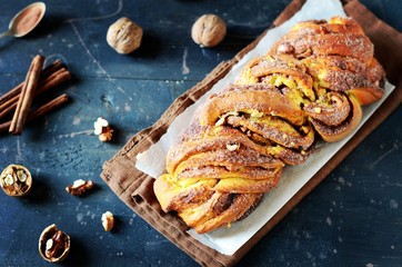 Cinnamon twisted loaf bread or babka on a dark wooden background, still life, rustic style