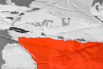 Red torn and crumpled paper poster with old ripped and peeling pieces of placard layers on billboard. Abstract urban grunge background.