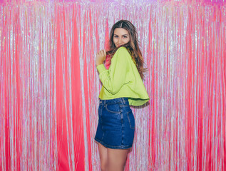 Young happy girl on the background of a pink festive curtain at a birthday party