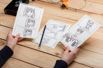 Artist drawing an anime comic book in a studio.