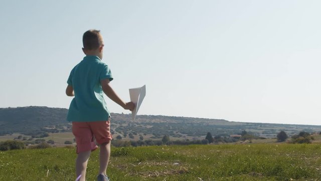 Back view of happy child launches paper airplane outdoors