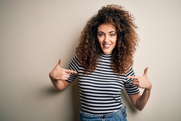 Young beautiful woman with curly hair and piercing wearing casual striped t-shirt looking confident...
